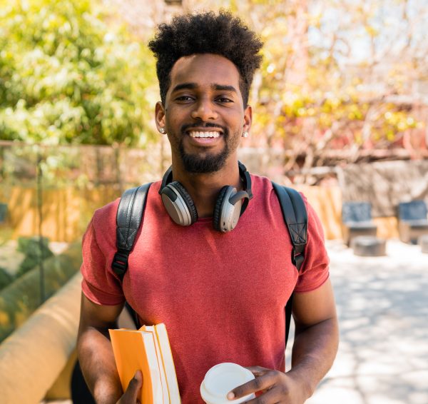 Portrait of young afro university student holding his books in campus. Education and lifestyle concept.